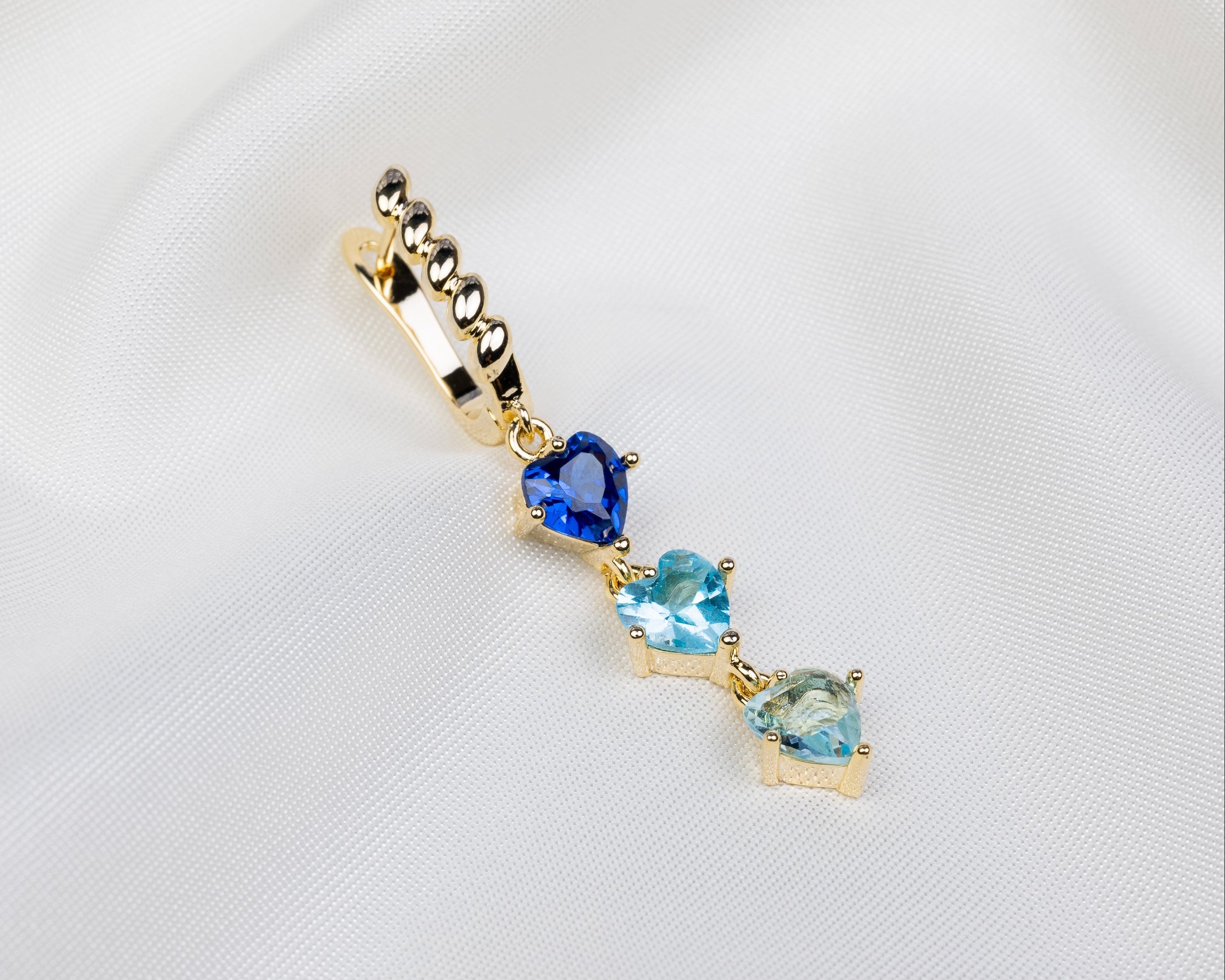 Handgemaakte 14k gold plated gedraaide oorbel met een hanger van drie blauwe zirkonia harten 