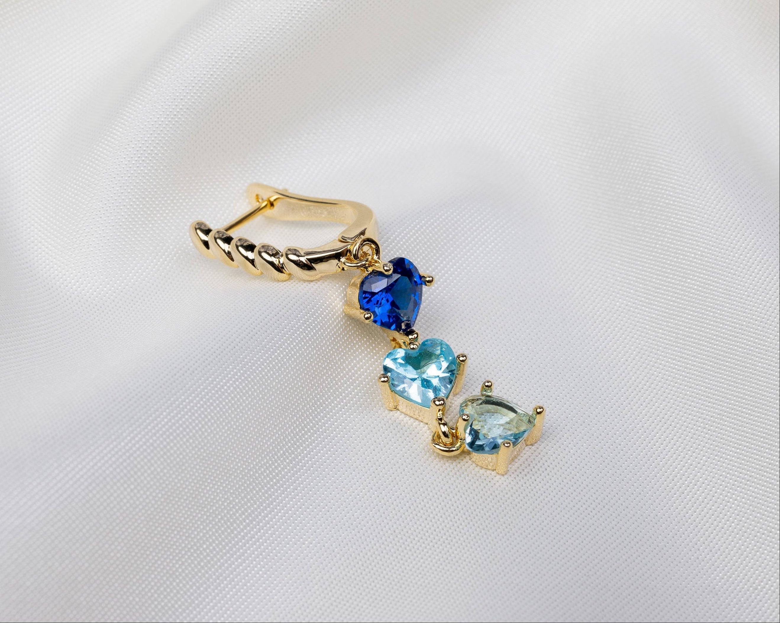 Handgemaakte 14k gold plated gedraaide oorbel met een hanger van drie blauwe zirkonia harten 