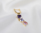 Handgemaakte 14k gold plated gedraaide oorbel met een hanger van drie paarse zirkonia harten 